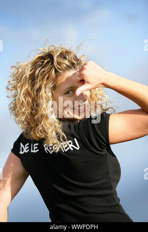 Woman stood outdoors pointing at logo on back of t-shirt Stock Photo