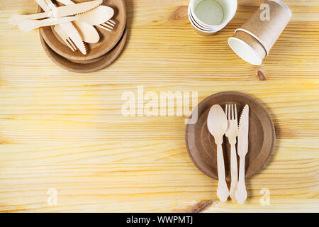 Brown paper cups, plates, wooden cutlery on wooden background. Recycling concept. Top down view, horizontal image with copy space Stock Photo