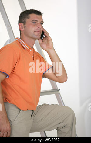 Man making call next to step-ladder Stock Photo