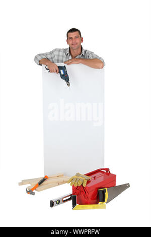 Man holding drill next to blank advertising panel Stock Photo