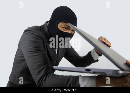 Concentrated trained masked computer hacker at stealing data from computer. Stock Photo