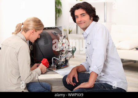 Couple repairing broken television Stock Photo