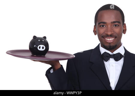 Waiter holding a piggy bank on his tray Stock Photo