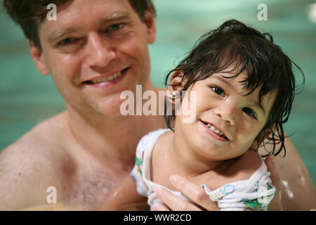 Father and toddler boy swimming in pool Stock Photo