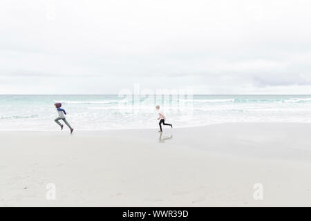 young boy and girl running on the beach in Carmel, California