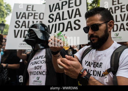 Madrid, Spain. 16th September, 2019. A man preparing an electronic cigarette for vaping during a protest in front of the Healthcare Ministry, defending the use of electronic cigarettes against tobacco. Placards behind reads 'Vaping safes lives'. Protesters are demanding not an equal treatment between tobacco and electronic cigarettes. Credit: Marcos del Mazo/Alamy Live News Stock Photo