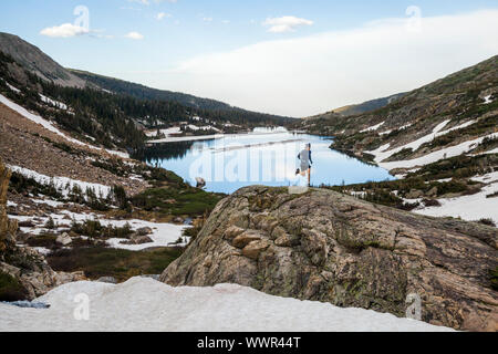 A man runs up a rock outcrop above Lake Isabelle, Indian Peaks Wilderness, Colorado. Stock Photo