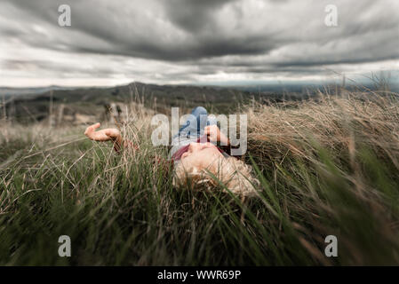 Young boy lying in tall grass Stock Photo