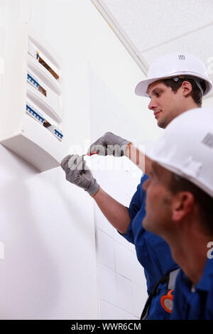 Two electrical workers installing fuse box Stock Photo