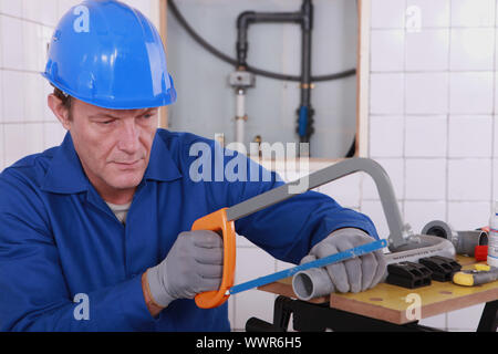 Plumber sawing plastic pipe Stock Photo