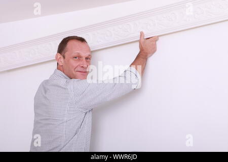 Decorator fixing coving to a ceiling Stock Photo