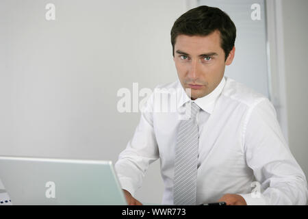 Stern businessman sat at his desk Stock Photo
