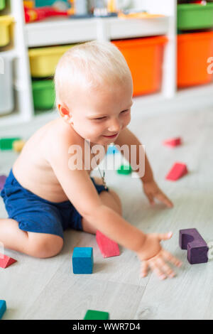 Cute baby boy playing with building blocks in kid's room Stock Photo