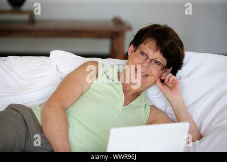 Woman laying in bed with laptop Stock Photo