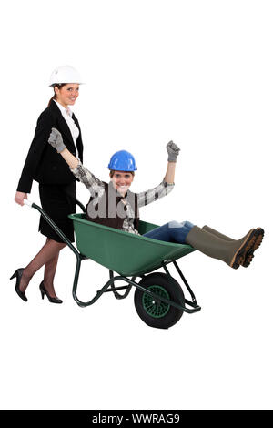 businesswoman carrying a craftswoman in a wheelbarrow Stock Photo - Alamy