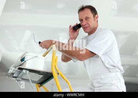 painter on ladder making a call Stock Photo