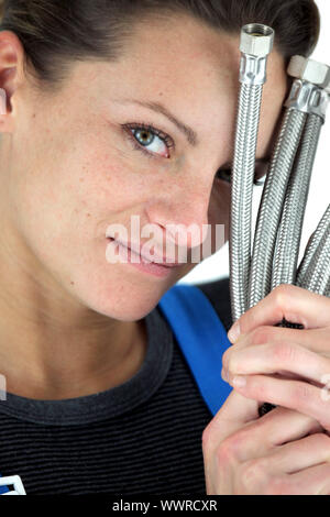 Female plumber holding pipes Stock Photo
