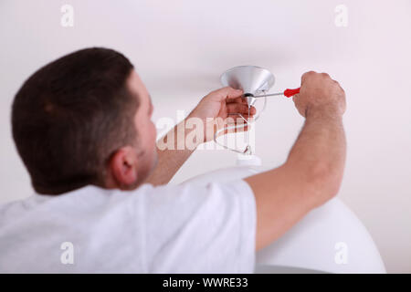 Man repairing ceiling light with screwdriver Stock Photo