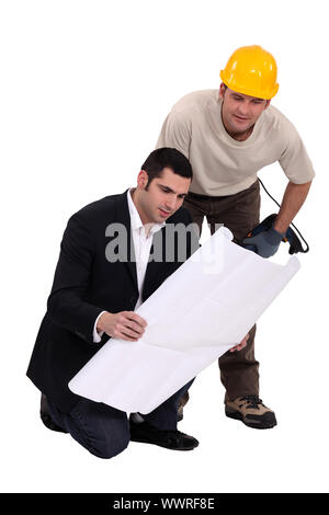 Construction worker consulting with an engineer over a drawing Stock Photo