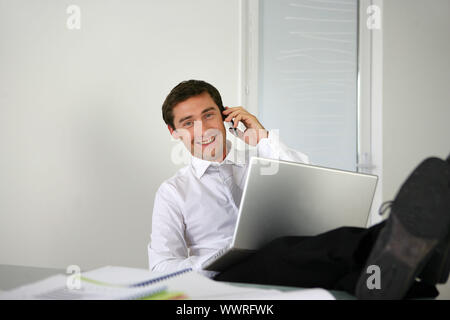 Businessman sat with his feet on the desk Stock Photo