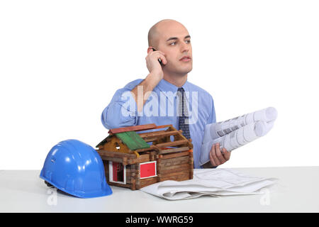 Architect sat at desk with model house Stock Photo