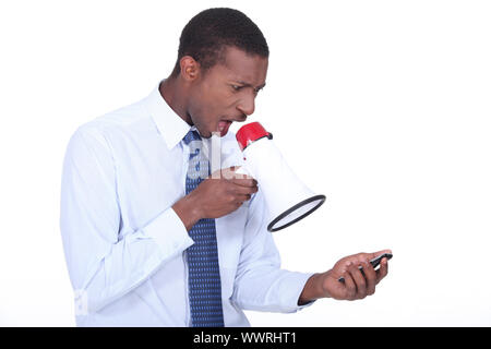 Man shouting through a megaphone at a cellphone Stock Photo