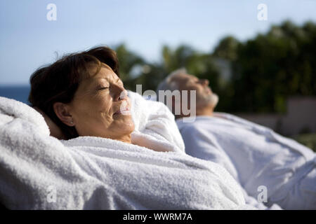 Couple laying outside in bathing robes Stock Photo
