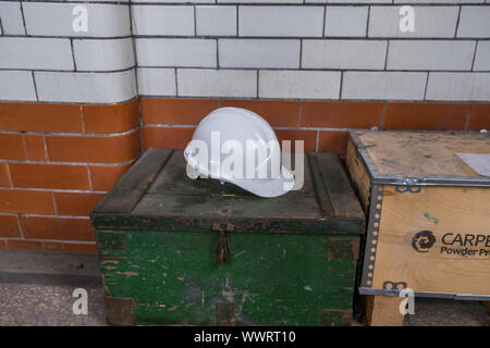 White hard hat resting on a wooden box in engineers workshop. Stock Photo