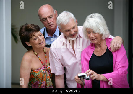 Two elderly couple looking at photos on digital camera Stock Photo