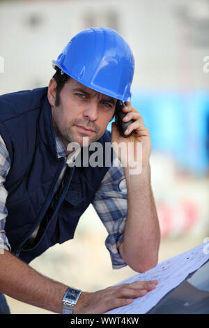 Foreman  checking plans whilst on the phone Stock Photo