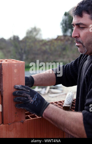 Mason working on unfinished brick wall Stock Photo
