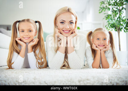 Portrait of three nice cute lovely attractive winsome cheerful positive people pre-teen girls mom mum mommy lying resting on carpet in light white Stock Photo