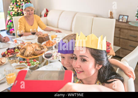 Young Australian mother with her son doing selfie photo while wearing paper crowns during Christmas celebration Stock Photo