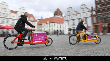 Greifswald, Germany. 16th Sep, 2019. Two men ride with load bikes through the old town of Greifswald. Dragged recording with wipe effect. From 16 September 2019, three different load bikes can be borrowed free of charge in Greifswald as part of the EU project 'Cobium' (Cargo bikes in urban mobility). The project aims to analyse the areas in which the use of load bikes makes economic, social and ecological sense and can ultimately replace motor vehicle journeys. Three other cities in the southern Baltic region are involved, Växjö in Sweden, Gdynia and S·upsk in Poland. Credit: dpa picture allia Stock Photo