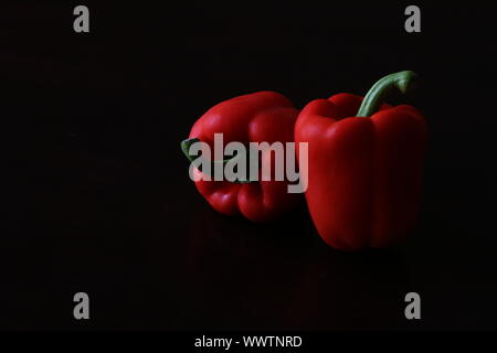 Sweet red capsicum peppers isolated on black background Stock Photo