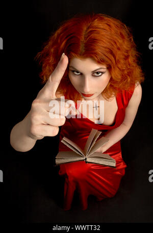 redhead religious lady with a book showing finger (focus on hand) Stock Photo