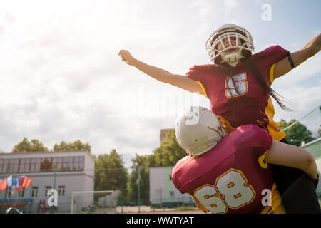 Image of two American football sportswoman wearing helmets with their hands to side against cloudy sky on summer day Stock Photo
