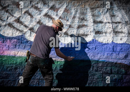 Graffiti artist painting colorful artwork with aerosol spray on the wall Stock Photo