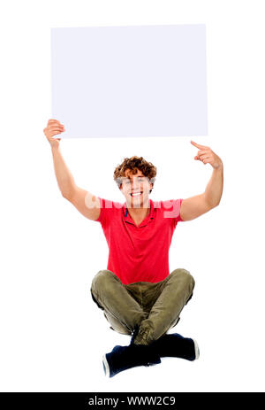 Good looking cool guy pointing towards white blank billboard, seated on floor Stock Photo