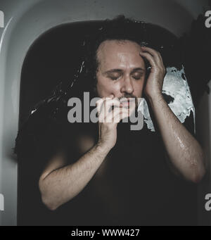 Satan, Fallen angel, man in a bathtub with black water and wings, submerged, depression, loss Stock Photo