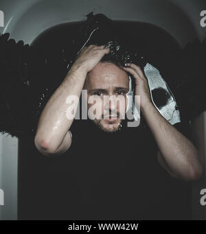 Face, Fallen angel, man in a bathtub with black water and wings, submerged, depression, loss Stock Photo