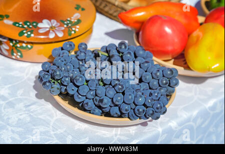 Still life: grapes on a plate on a white tablecloth table. Stock Photo
