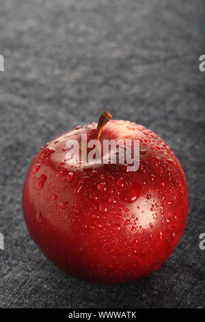 red apple with drops of water on blue denim background Stock Photo