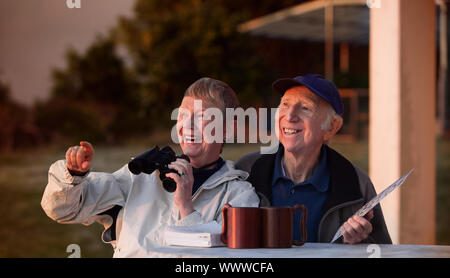 Happy elderly bird watchers outside in jackets Stock Photo
