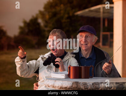 Excited woman with binoculars with and man in hat Stock Photo