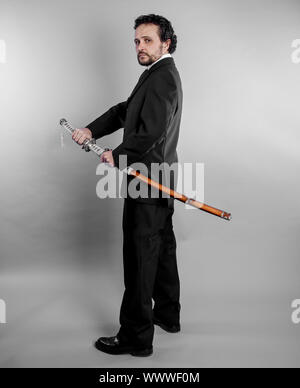 Security Businessman in black suit and armed japanese sword on gray background Stock Photo