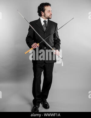 Businessman in black suit and armed japanese sword on gray background Stock Photo