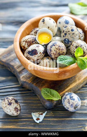 Quail eggs and shells with the yolk in a wooden bowl. Stock Photo