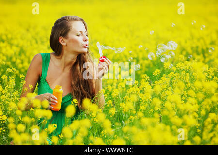 woman start soap bubbles on yellow flower field Stock Photo - Alamy image.