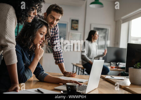 Three young designers working on a laptop in an office Stock Photo